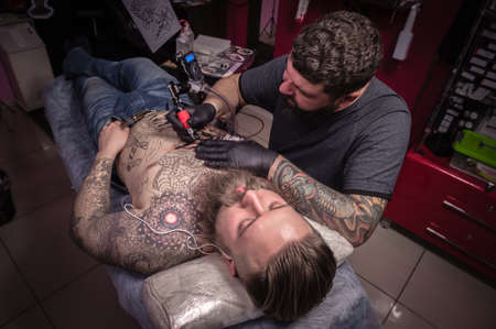 Tattoo specialist demonstrates process of making a tattoo his salonの写真素材