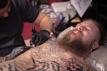 Tattoo master does a tattoo in the Studioの写真素材