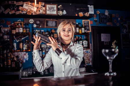 Experienced girl bartending demonstrates his skills over the counter while standing near the bar counter in barの写真素材