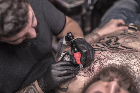 Tattooer demonstrates process of making a tattooの写真素材