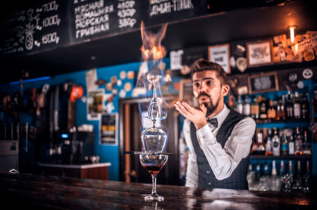Professional bartender decorates colorful concoction while standing near the bar counter in nightclubの写真素材