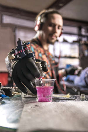 Hand of tattoo artist and a tattoo gun.の写真素材