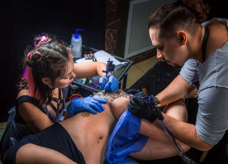 Tattooist does tattoo on the skin of his client in tattoo studioの写真素材