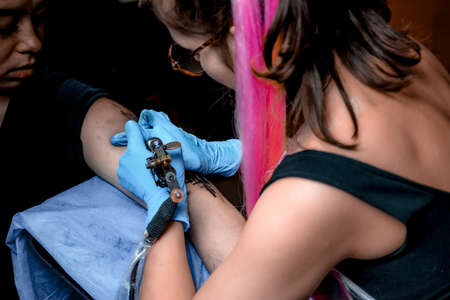Tattooist working on professional tattoo machine device in a workshop studioの写真素材
