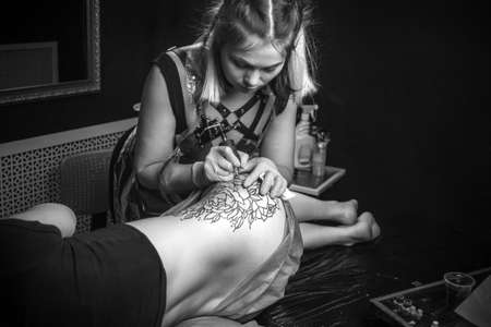Professional tattooist makes a tattoo on the clients the salonの写真素材