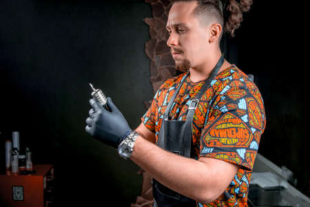 Tattoo master with a tattoo gun in his salonの写真素材