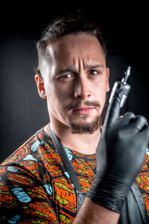 Master of the art of tattooing with a tattoo gun in tattoo studioの写真素材