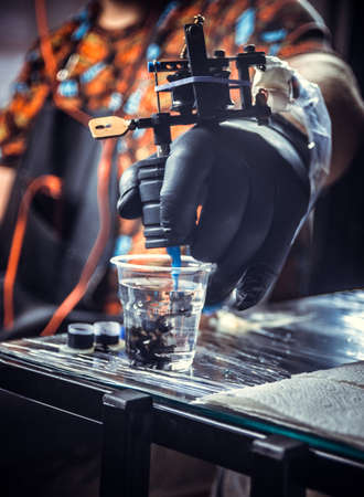 Hand of professional tattooist with a tattoo machine.の写真素材