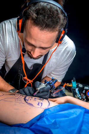Master of the art of tattooing makes tattoo pictures in the salonの写真素材