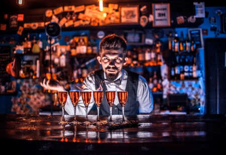 Young bartending places the finishing touches on a drink in the night clubの写真素材