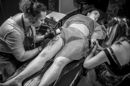 Professional tattooer demonstrates the process of getting tattoo in tattoo studioの写真素材