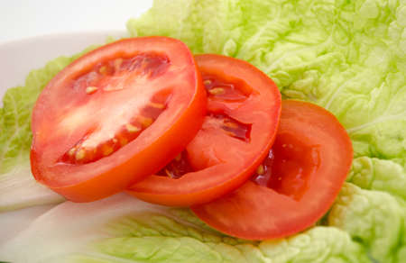 Chopped tomato slices on a piece of lettuceの写真素材