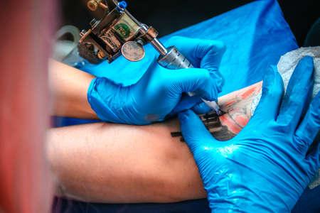 Professional tattoo artist makes a tattoo on the clients tattoo studioの写真素材