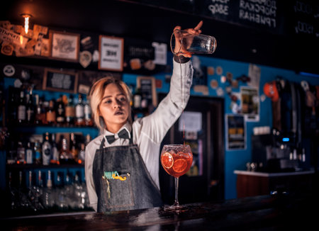 Confident girl barman intensely finishes his creation at barの写真素材
