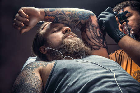 Tattoo specialist showing process of making a tattoo in tattoo studioの写真素材