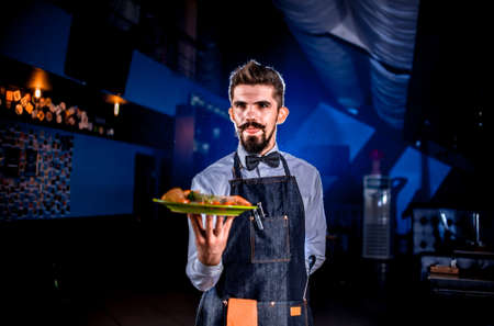 Friendly waiter carries cooked dish in the restaurant.の写真素材