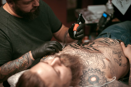Master does tattoo on the skin of his client in tattoo parlourの写真素材