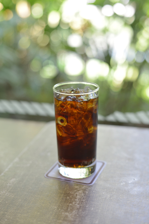 glass of cola on the table with bokeh backgroundの写真素材