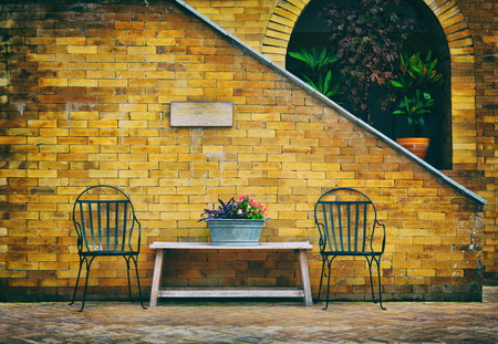 Retro style photo of chairs and wooden table with  brick wall in backyardの写真素材