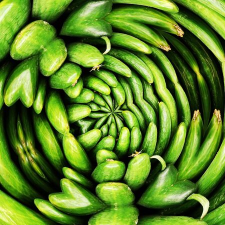 intricate swirl pattern from many fresh organic cucumbers at a farmers market