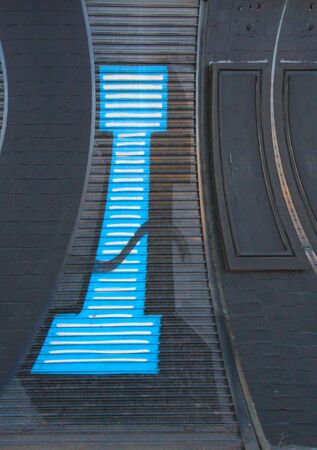 distorted  perspective view of huge capital letter I in blue paint on shutter doors on a dark background into shapes patterns and intricate designsの写真素材