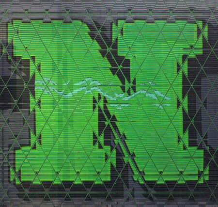 triangular mosaic view of huge capital letter N  in green paint on shutter doors on a dark background into shapes patterns and intricate designsの写真素材