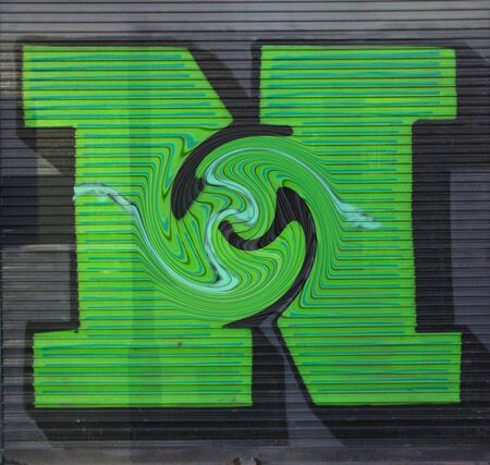 Twisted view of huge capital letter N  in green paint on shutter doors on a dark background into shapes patterns and intricate designsの写真素材
