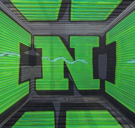 cube shape view of huge capital letter N  in green paint on shutter doors on a dark background into shapes patterns and intricate designsの写真素材