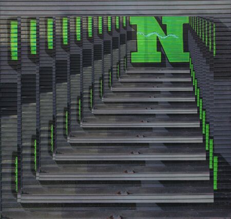 concentric diminishing perspective view of huge capital letter N  in green paint on shutter doors on a dark background into shapes patterns and intricate designsの写真素材