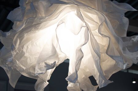 Crumpled paper white lamp on the ceiling. The design of the apartment.の写真素材