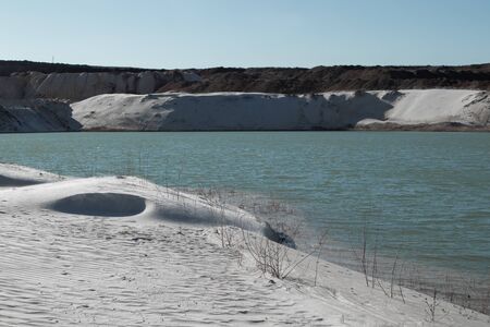 Small waves on blue water and a sandy beach. Pond on a sand quarry.の写真素材