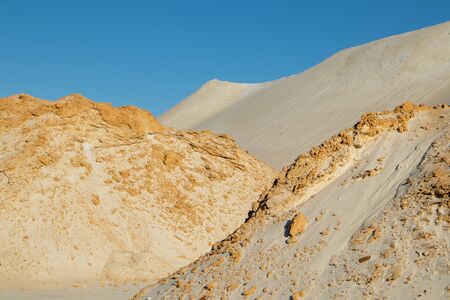 Desert landscape. Dunes of orange sand, sunny day, shadows on the sand, wind wrinkles on the sand, dry small bushes.の写真素材