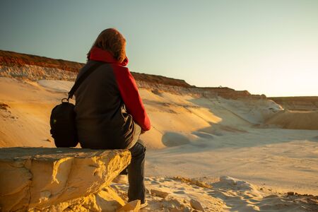 The girl in the desert sits on a stone