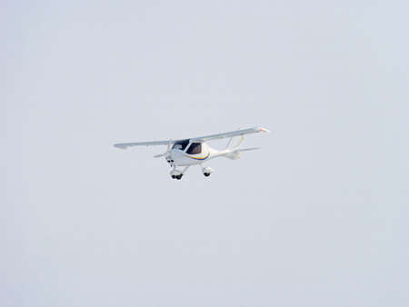 Zoom photo of small propeller airplane landing to small airport.