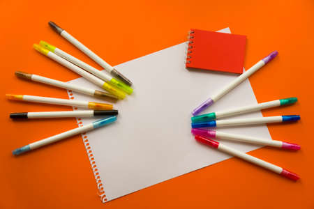 Creative kids concept. Colorful crayon paints and blank notepad on orange color background, red...