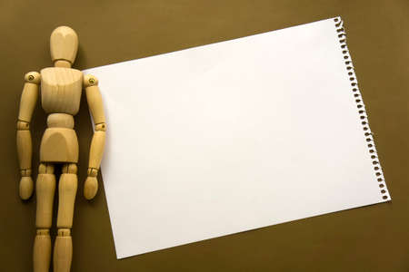 Wooden doll and a blank piece of paper. Wooden mannequin with sheets of paper concept, blank space. Creativity and artの写真素材