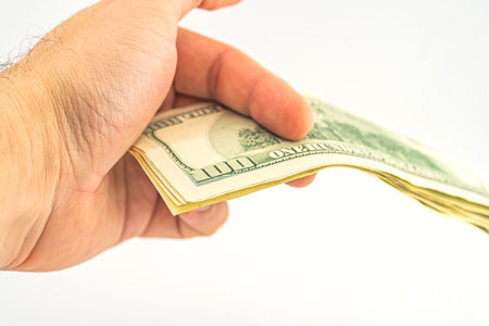 Hand holding money isolated on white background. One hundred Dollars bill on man hand to paying and giving. Business and Finances concept. 100 Dollars Cash Money. Hands with money American dollars.の写真素材