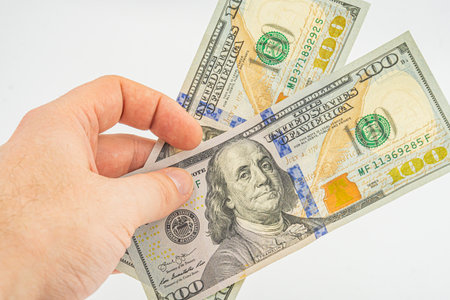 Hand holding money isolated on white background. One hundred Dollars bill on man hand to paying and...