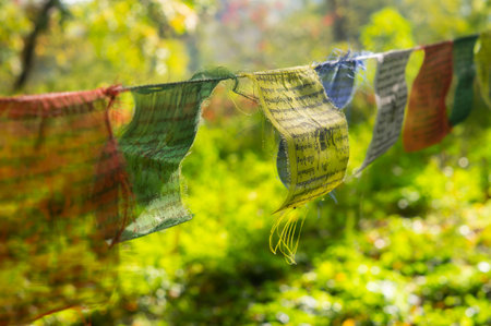 Tibetan prayer flags hanging from a string, symbolizing peace, harmony, and religious devotion in a natural setting, possibly an outdoor Buddhist retreat center The vibrant flags represent the fiveの写真素材