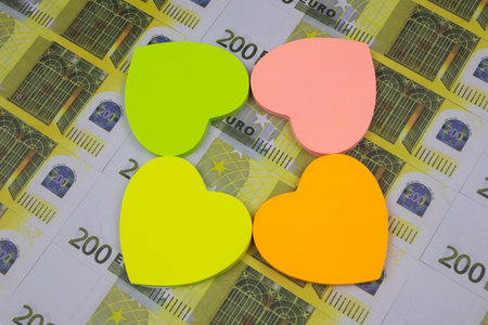 Colored heart-shaped stickers neatly laid out on 200 Euro banknotes. Close-upの写真素材