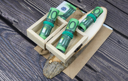 100 euro banknotes with bundles and rolls of money in wooden boxes on cut woodの写真素材