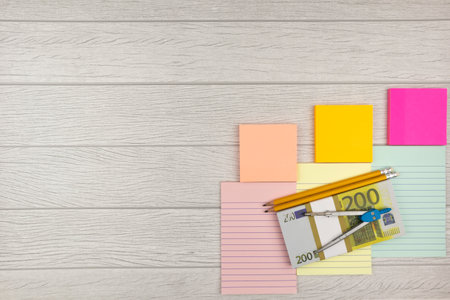 Business, financial or wealth concept with 200 Euro banknotes, a mathematical compass and sticky memos over a light wood background with copyspace placed to the cornerの写真素材