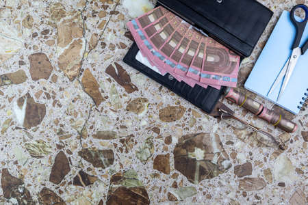 Financial success or business concept in a flat lay still life on a stone background with fanned Euro bills and purse, scissors, eyeglasses, notebook and pencil with copyspace. Top viewの写真素材