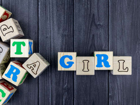 Colourful wooden toy alphabet blocks spelling word - Girl over a dark grey plank background with copyspace. Flat lay, top viewの写真素材