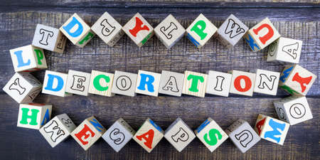 Word - Decoration - in colorful alphabet letters on wooden cubes surrounded by a frame of additional random blocks over a textured textile background. Flat lay, top viewの写真素材