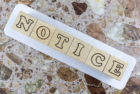 Notice or announcement concept with alphabet letters on wooden blocks arranged in a diagonal line on a sign over a marbled stone background with copyspace. Flat layの写真素材