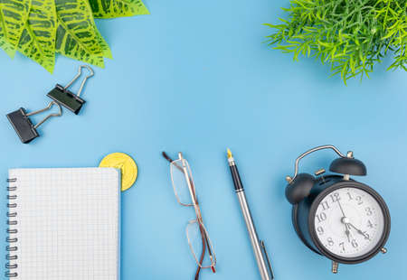 Business conceptual flat lay still life with crypto coin and alarm clock alongside a notepad,...