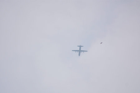 Silhouettes of an airplane and a small bird share the same cloudy sky suggesting themes of wildlife...