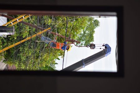 Electric utility workers performing maintenance on overhead power lines while using safety gear and...