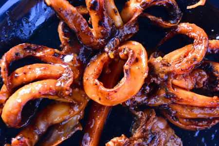 Macro food photo of sizzling grilled squid calamari ring with caramelized spicy glaze and curled...